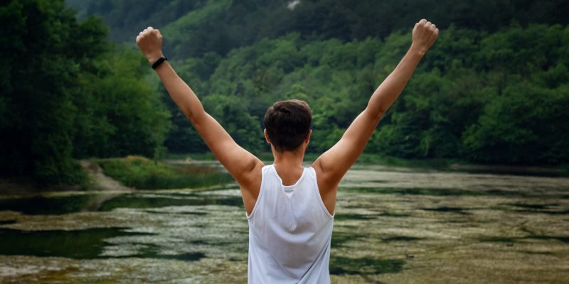 The young male hipster looking at the beautiful view at the lake
